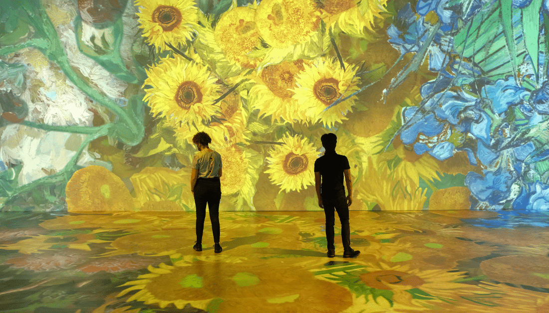 Two people looking at pictures of Sunflowers at Beyond Van Gogh